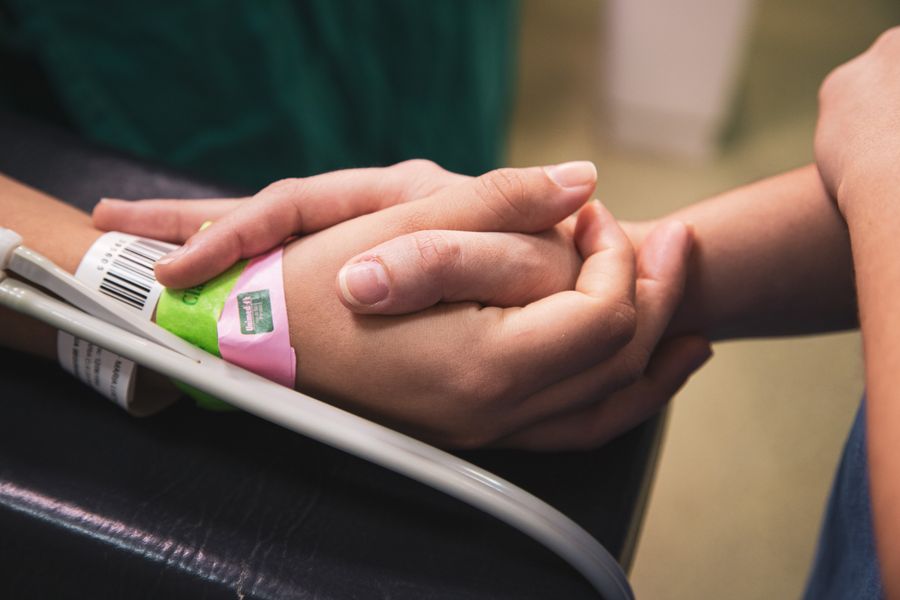 A carer holding the hand of a patient